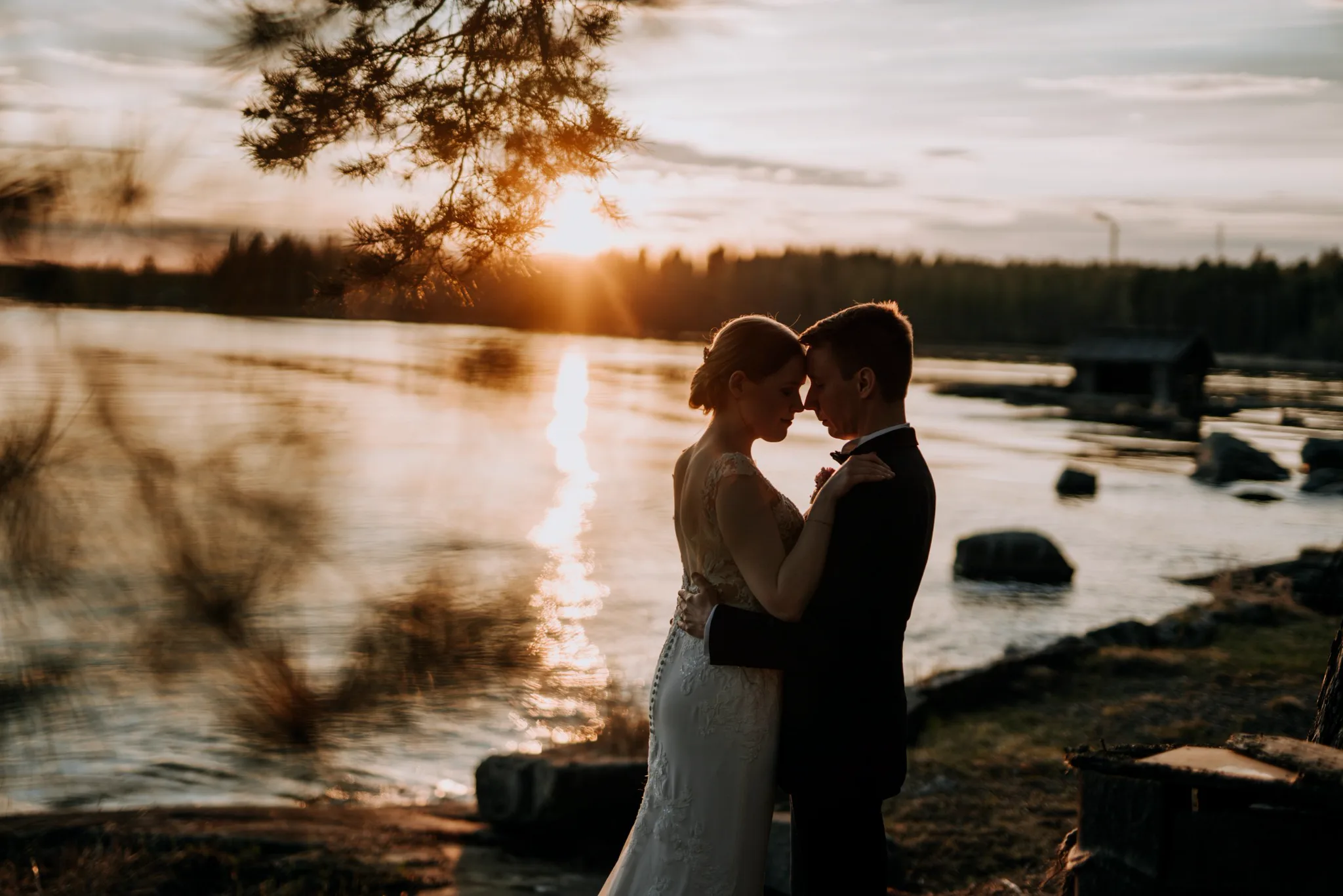 Hääpari halaa järvellä auringonlaskussa