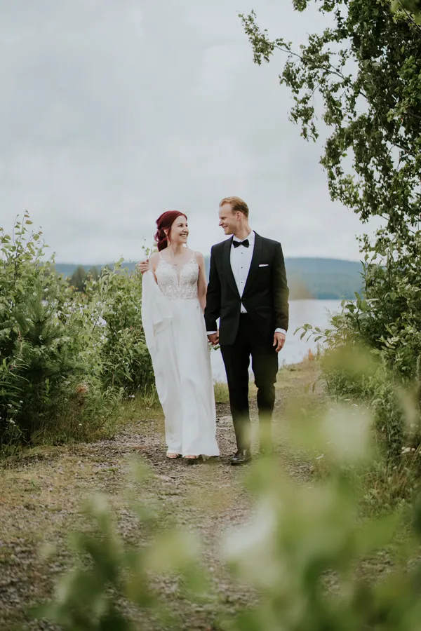 Hääpari kävelee järven rannalla