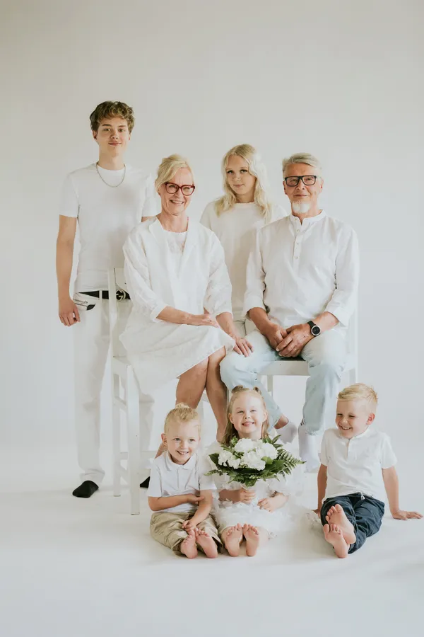 Suurperhe valkoisissa vaatteissa studiossa