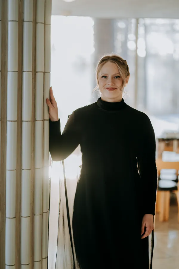 Valmistuja mustassa mekossa ikkunan valossa