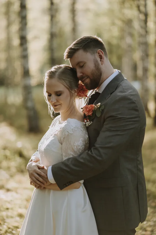 Hääpari syleilee toisiaan metsässä