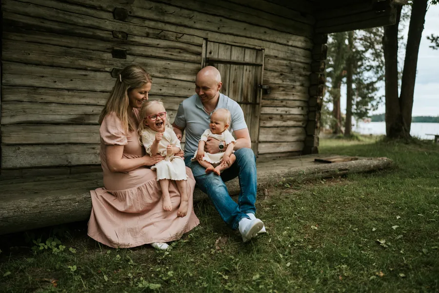 Perhe ja vauva istuvat vanhan rakennuksen edessä